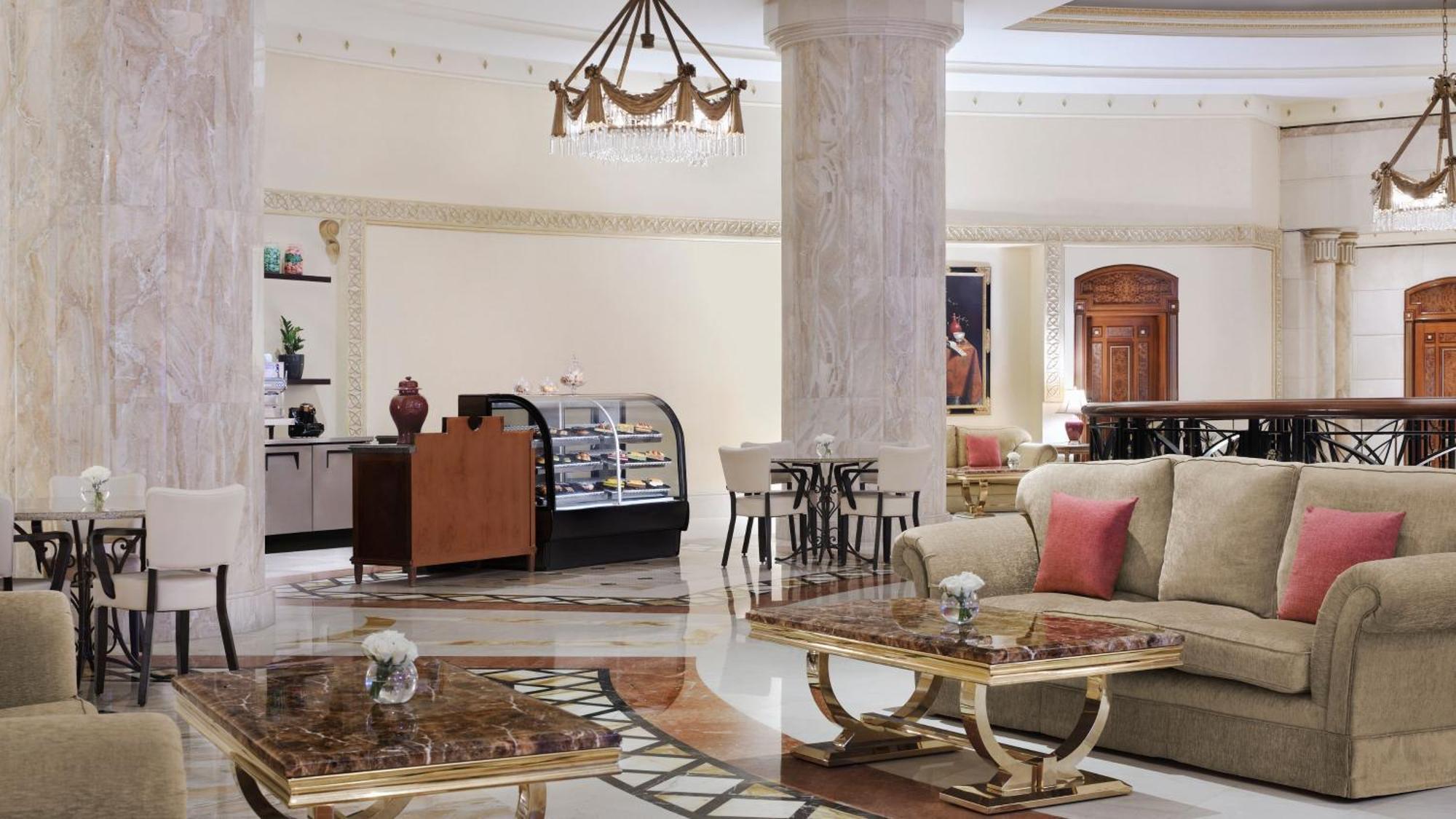 Hotel Intercontinental Dar Al Iman Madinah By Ihg Medína Exteriér fotografie The photo shows a luxurious hotel lobby or lounge area. It features elegant marble floors and tall columns. There are comfortable seating arrangements with a sofa and stylish tables that have marble tops. A display case for pastries or refreshments i