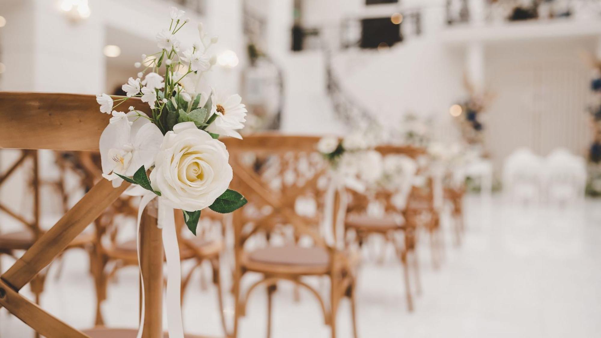 Hotel Intercontinental Dar Al Iman Madinah By Ihg Medína Exteriér fotografie The photo showcases a beautifully arranged event space, likely set up for a wedding or special occasion. In the foreground, wooden chairs are neatly lined up, some adorned with decorative floral arrangements. The flowers include white roses and small