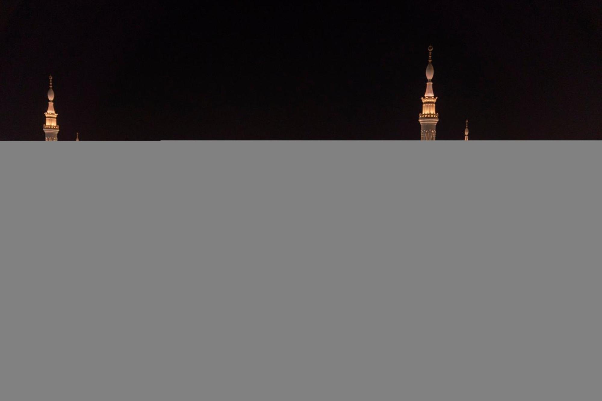 Hotel Intercontinental Dar Al Iman Madinah By Ihg Medína Exteriér fotografie The image appears to show a night scene featuring tall structures with pointed tops, likely minarets, illuminated against a dark background. The lighting creates a striking contrast, highlighting the architectural details of the structures. The overa