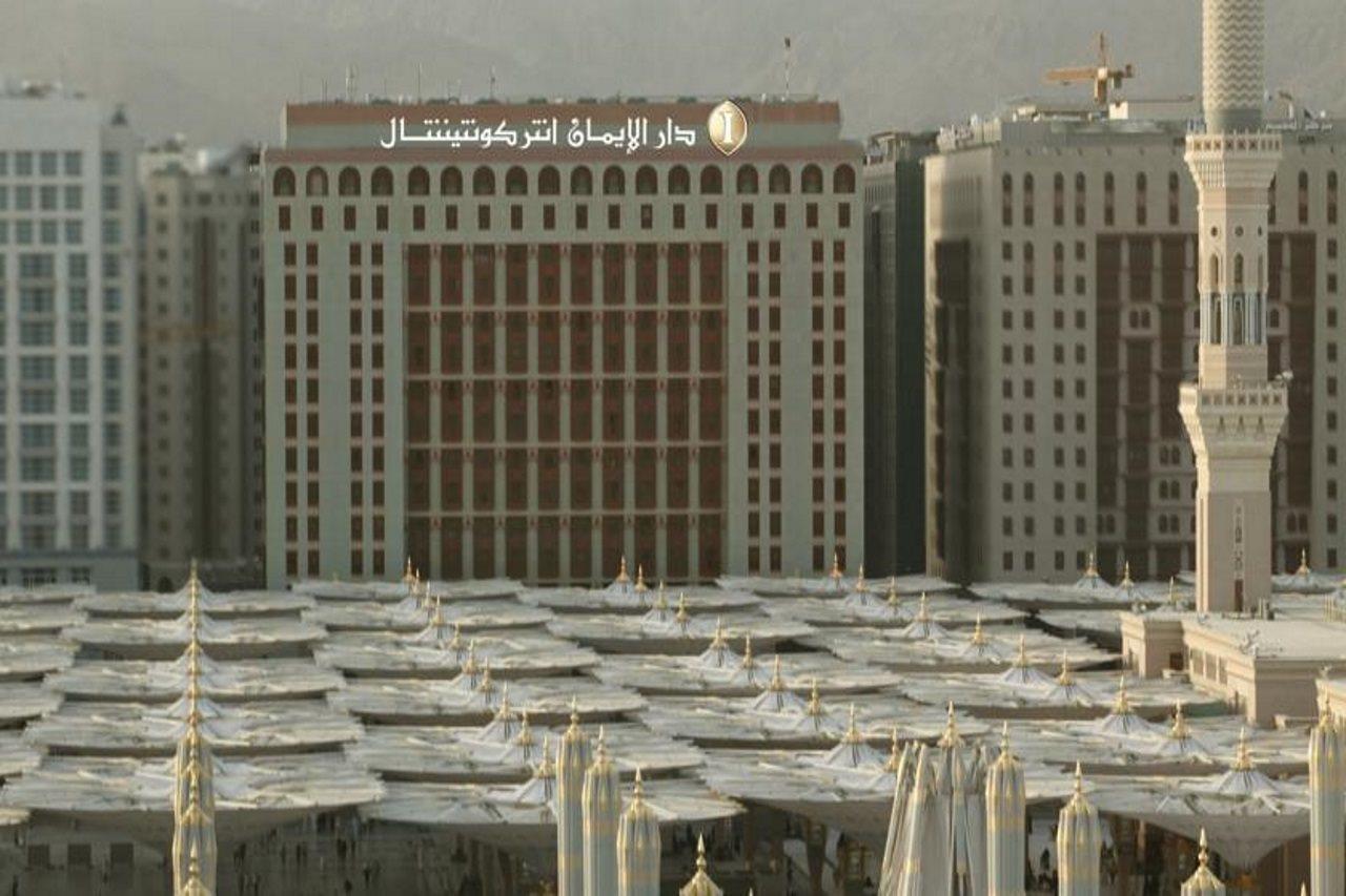 Hotel Intercontinental Dar Al Iman Madinah By Ihg Medína Exteriér fotografie The photo shows a view of a large building with a modern architectural design, which appears to be a hotel or a commercial establishment. In front of the building, there are several large white canopies that provide shade, likely in a public space or
